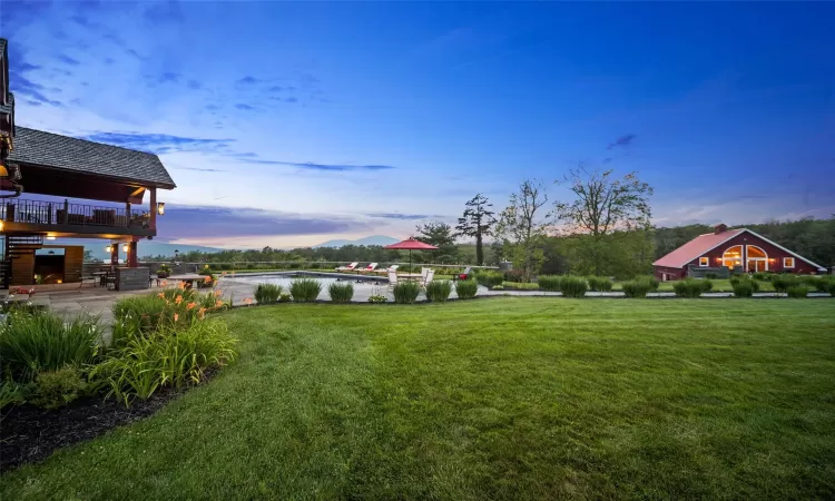 Yard at dusk featuring a patio area and a deck with water view