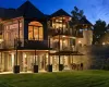 Back house at dusk featuring a lawn, a balcony, and a patio