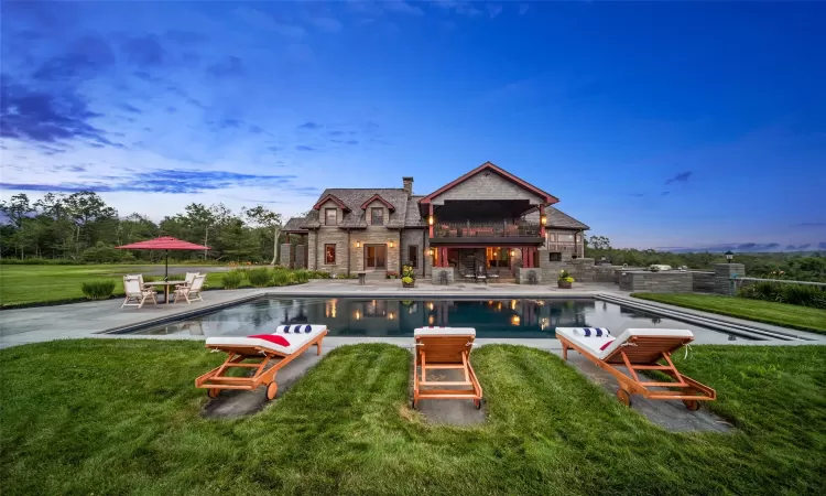 Pool at dusk featuring a yard and a patio