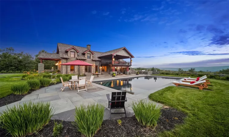 Pool at dusk featuring a patio and a lawn