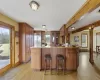 Kitchen featuring a kitchen bar, kitchen peninsula, stainless steel built in refrigerator, beam ceiling, and light hardwood / wood-style flooring