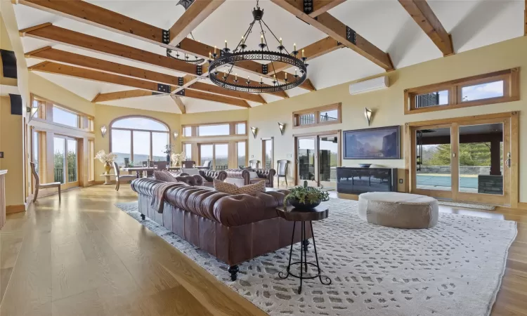 Living room with a chandelier, a wealth of natural light, light hardwood / wood-style floors, and a high ceiling