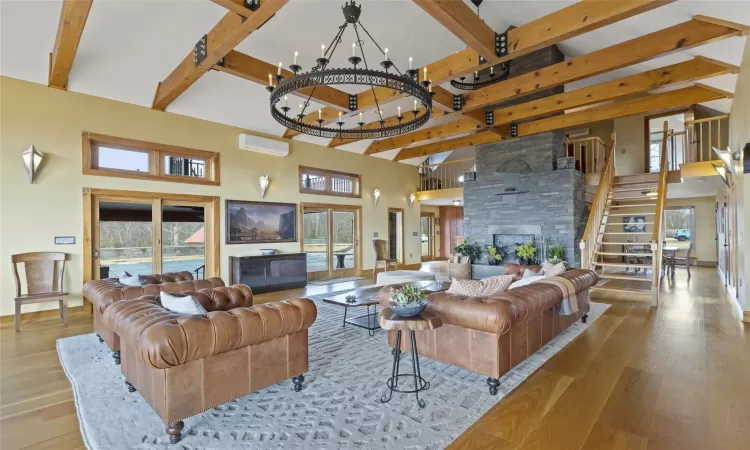 Living room with a wall mounted AC, a fireplace, and a high ceiling