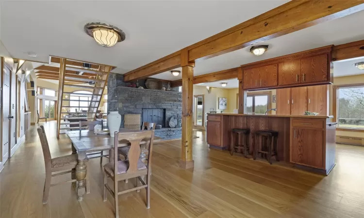 Dining room with a fireplace, beamed ceiling, and light hardwood / wood-style flooring