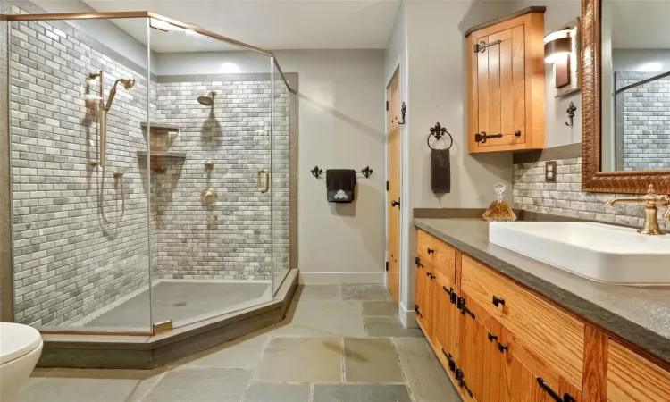 Bathroom featuring decorative backsplash, toilet, walk in shower, and vanity