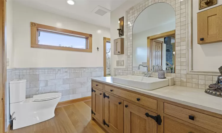 Bathroom with hardwood / wood-style flooring, vanity, toilet, and tile walls