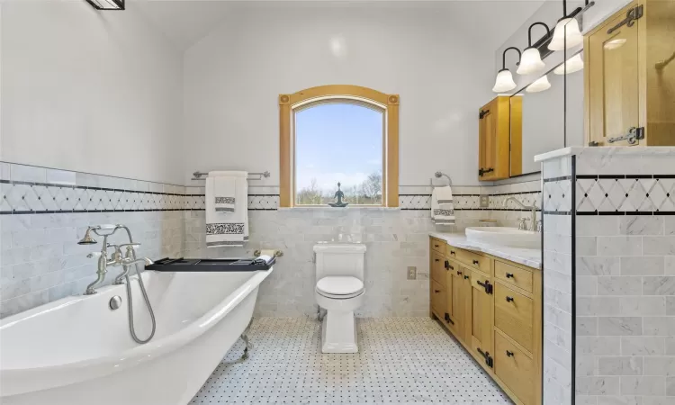 Bathroom with a tub, lofted ceiling, and tile walls