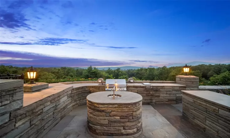 Patio terrace at dusk with area for grilling, a mountain view, and grilling area