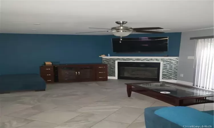 Living room with ceiling fan and a tile fireplace