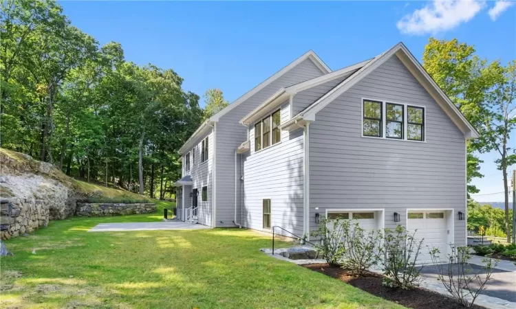 View of property exterior with a lawn and a garage