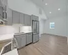 Kitchen with appliances with stainless steel finishes, gray cabinets, light hardwood / wood-style floors, and sink