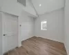 Spare room featuring light wood-type flooring and high vaulted ceiling