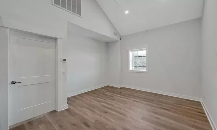 Spare room featuring light wood-type flooring and high vaulted ceiling