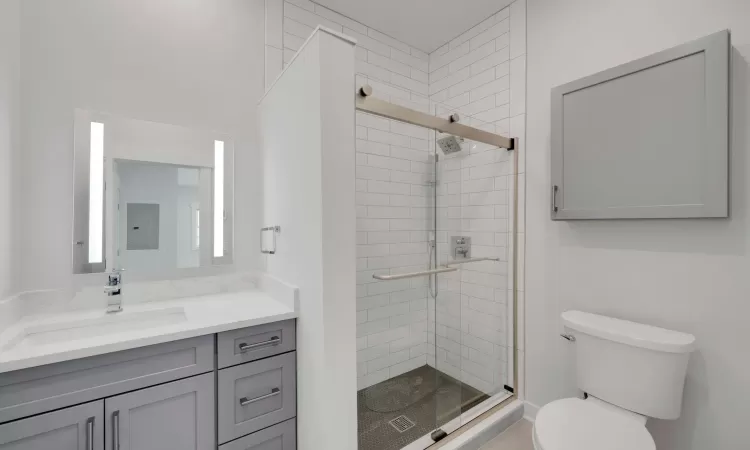 Bathroom featuring an enclosed shower, vanity, toilet, and electric panel