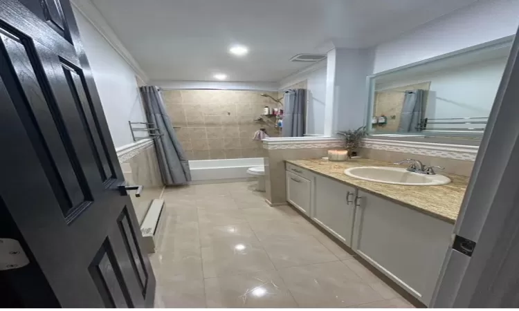 Full bathroom featuring tile patterned flooring, crown molding, toilet, vanity, and shower / tub combo