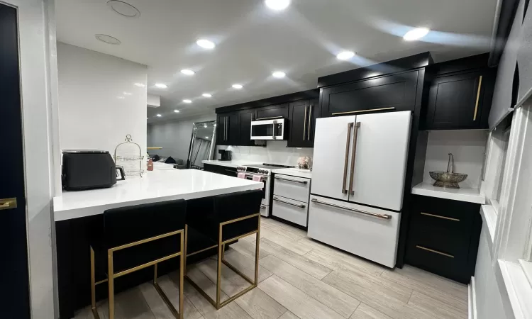 Kitchen with a kitchen breakfast bar, stove, and high end white fridge