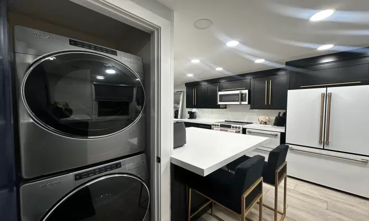 Laundry room with light hardwood / wood-style flooring and stacked washer and clothes dryer