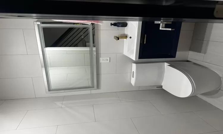 Bathroom featuring vanity, backsplash, tile patterned floors, toilet, and tile walls