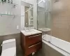 Full bathroom with vanity, toilet, enclosed tub / shower combo, and tile walls