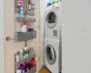 Laundry area featuring stacked washer / dryer and hardwood / wood-style flooring