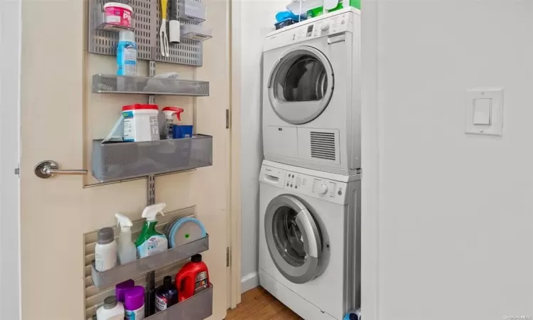 Laundry area featuring stacked washer / dryer and hardwood / wood-style flooring