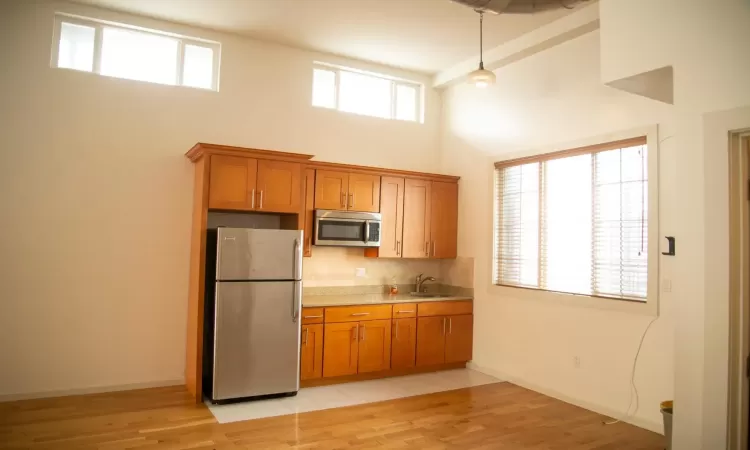 Kitchen featuring backsplash, stainless steel appliances, sink, a high ceiling, and hanging light fixtures