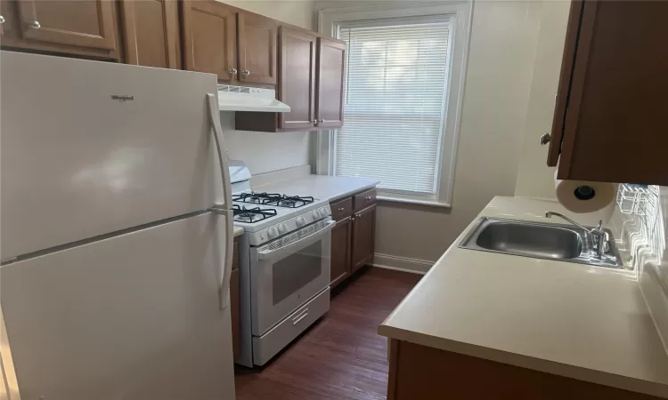 Kitchen featuring range with gas stovetop, dark hardwood / wood-style floors, white fridge, and sink