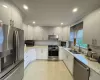 Kitchen featuring white cabinetry, sink, light stone countertops, and stainless steel appliances