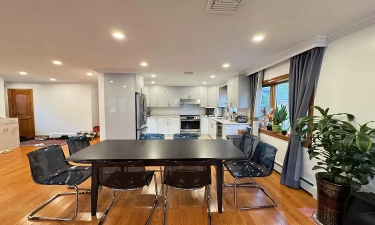 Dining area with light hardwood / wood-style flooring, sink, crown molding, and a baseboard radiator