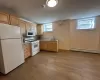 Kitchen featuring hardwood / wood-style floors, white appliances, a baseboard heating unit, sink, and light brown cabinetry