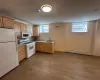 Kitchen with hardwood / wood-style floors, white appliances, sink, light brown cabinetry, and a baseboard radiator