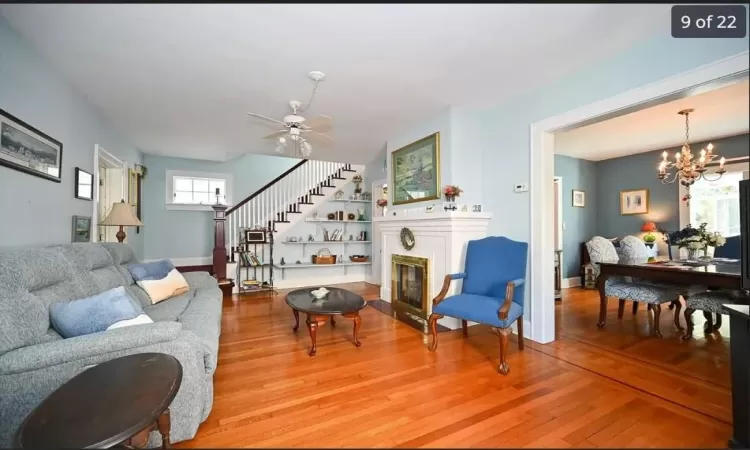 Living room with ceiling fan with notable chandelier and light hardwood / wood-style floors