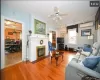 Living room featuring hardwood / wood-style floors, an AC wall unit, rail lighting, a brick fireplace, and ceiling fan