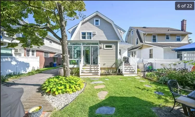 Back of property featuring a lawn and a sunroom