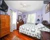 Bedroom featuring multiple windows, dark hardwood / wood-style floors, a wall unit AC, and ceiling fan