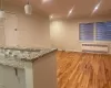 Bar featuring light wood-type flooring, light stone counters, radiator, crown molding, and hanging light fixtures