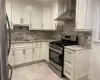 Kitchen featuring light stone counters, wall chimney range hood, sink, and appliances with stainless steel finishes