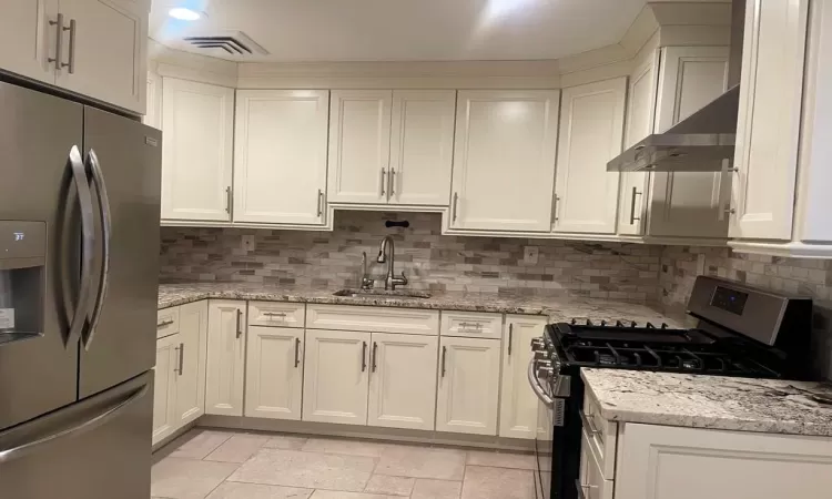 Kitchen with sink, light stone countertops, stainless steel appliances, and tasteful backsplash