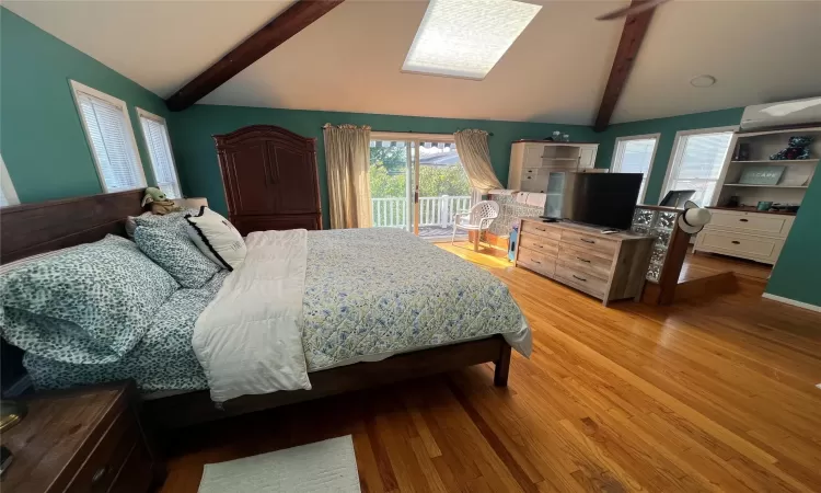 Bedroom featuring vaulted ceiling with beams, and light hardwood / wood-style flooring