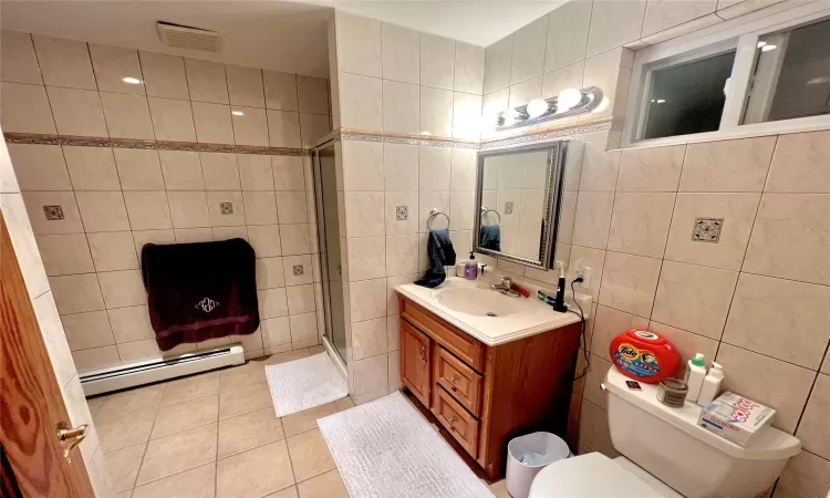 Bathroom featuring vanity, a shower with door, tile patterned floors, tile walls