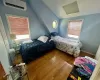 Bedroom with hardwood / wood-style flooring, an AC wall unit, baseboard heating, and lofted ceiling