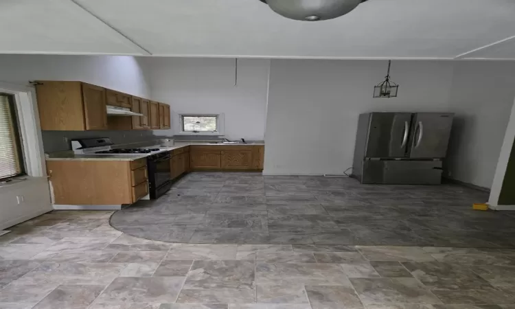 Kitchen featuring gas stove, stainless steel refrigerator, sink, and pendant lighting