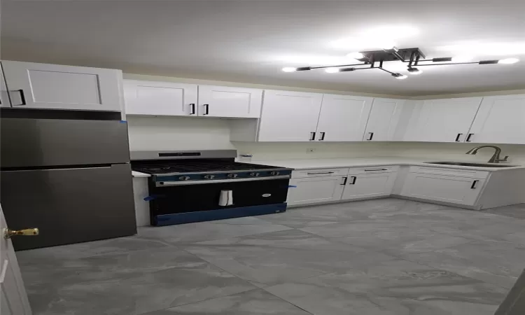 Kitchen featuring sink, stainless steel fridge, a notable chandelier, gas stove, and white cabinetry