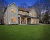 Back house at dusk with a yard and covered porch