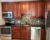 Kitchen with backsplash, dark stone countertops, sink, and appliances with stainless steel finishes