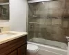 Full bathroom featuring shower / bath combination with glass door, vanity, and toilet