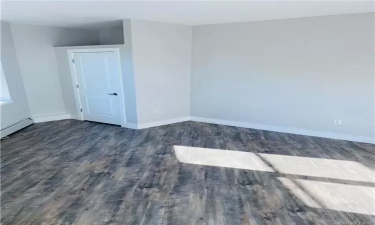 Spare room featuring dark hardwood / wood-style floors and a baseboard radiator