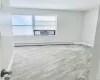 Empty room with a wealth of natural light, light wood-type flooring, baseboard heating, and cooling unit