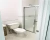 Bathroom with tile patterned floors, vanity, a shower with door, tile walls, and toilet