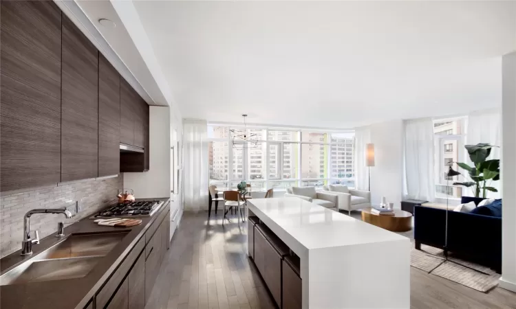 Kitchen featuring sink, a center island, stainless steel gas cooktop, tasteful backsplash, and expansive windows